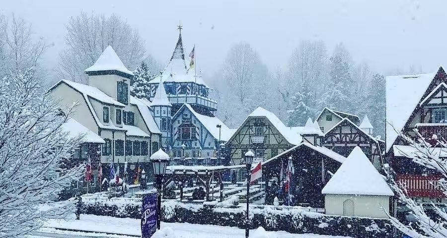 Helen Alpine-style village covered in fresh snow with timber buildings, flags, and winter snowfall in progress